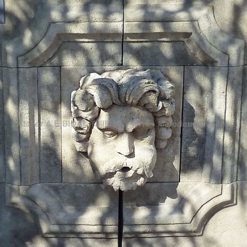 Visage d'Eole sculpté à la main sur le fronton de notre fontaine rustique en pierre.