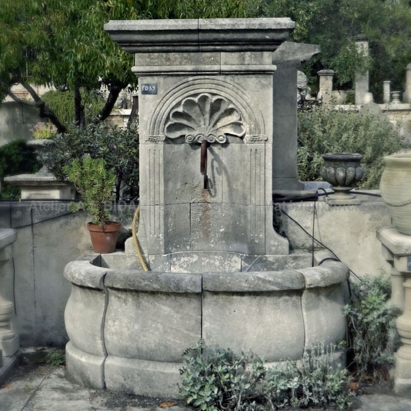 Garden wall fountain in a rustic style crafted by the stone mason Alain Bidal in Provence.