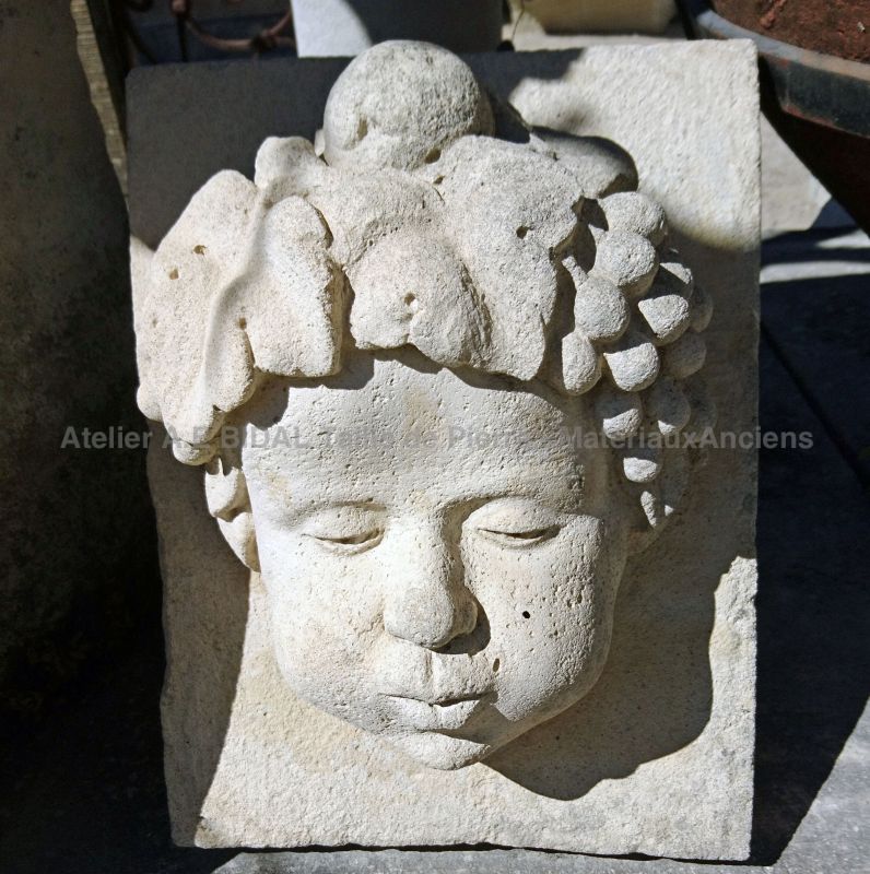 Sculpture en béton : visage féminin ornée de grappes de raisins