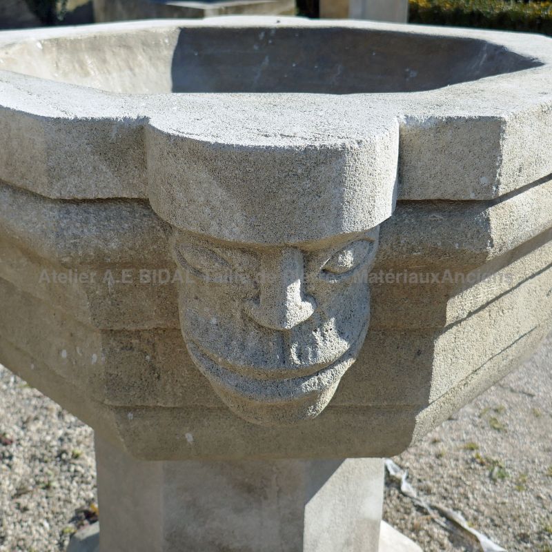 Détail de l'une tête sculptée à la main sur notre bénitier en pierre