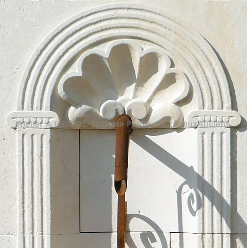 Détail des sculptures réalisées à la main sur le fronton de notre jolie fontaine murale en pierre blanche.