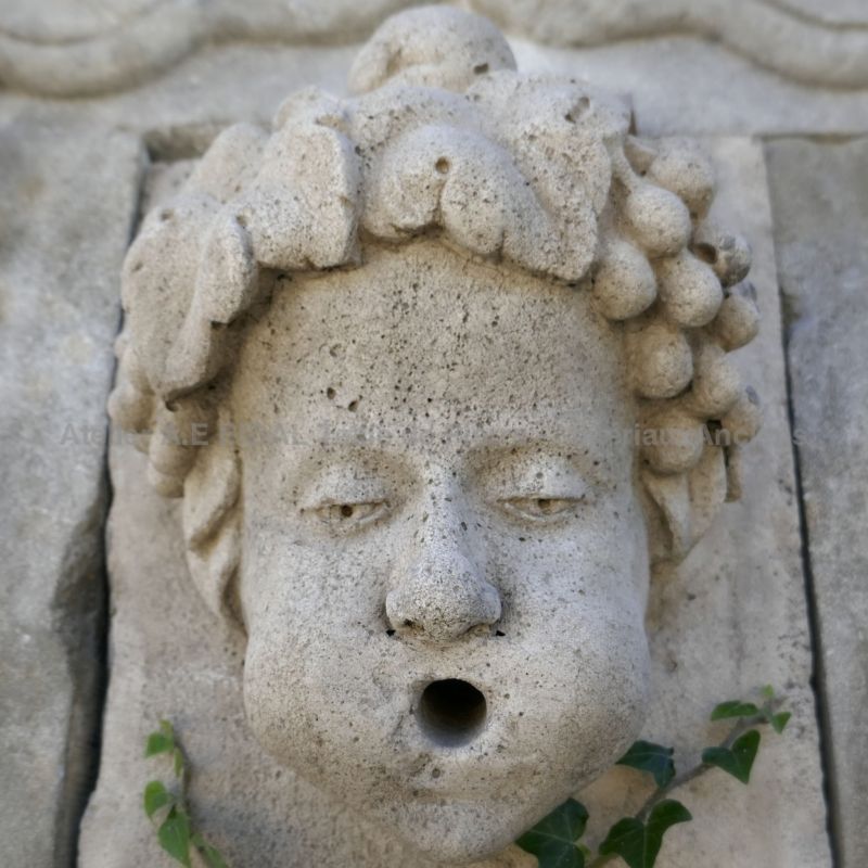 Détail de la sortie d'eau sculptée en pierre sur le fronton de notre fontaine de jardin en pierre de Provence | Vente de fontaines et bassins en pierre en Provence chez l'Atelier Bidal.
