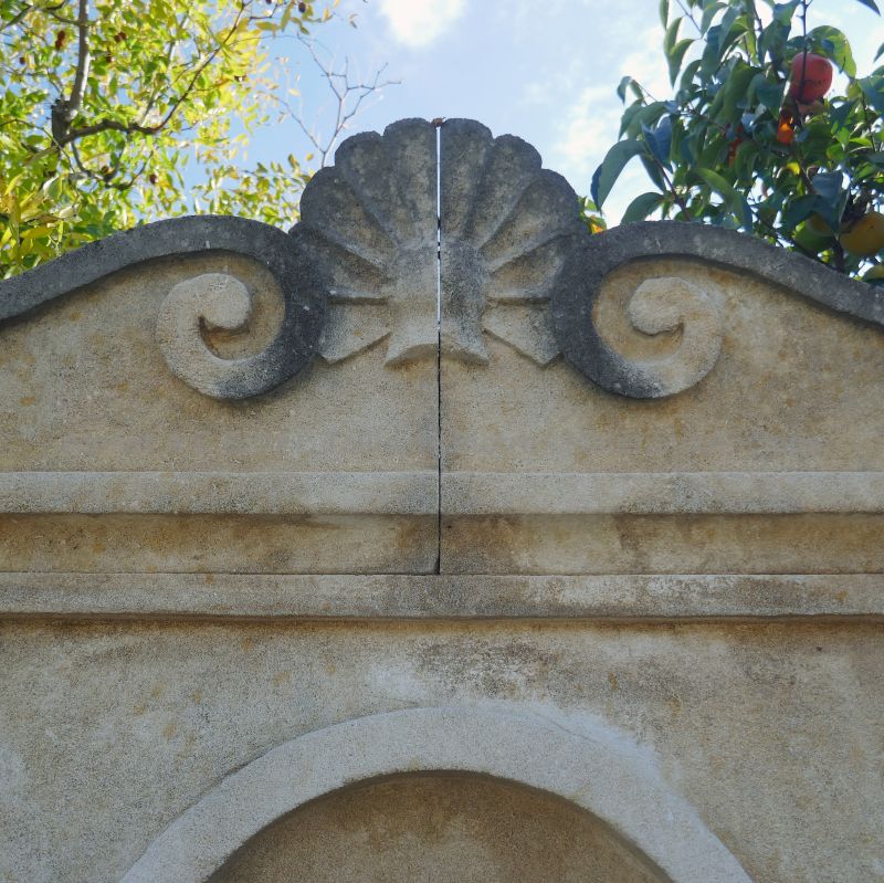 Detailed picture of the cornice hand-sculpted with a shell on our garden wall fountain in stone