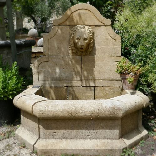 Fontaine murale avec tête de lion sculptée à la main par le tailleur de pierre provençal Alain BIDAL.