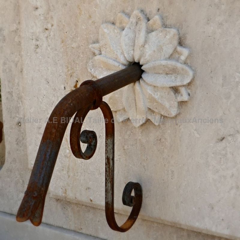 Sortie d'eau en fer forgé ornée d'une rosace sculptée à la main sur le fronton de notre fontaine de jardin décorative | Atelier Alain BIDAL